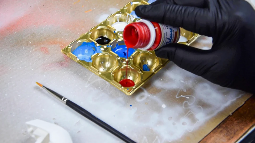 Zwei Hände in schwarzen Handschuhen mischen Modellbaufarben in einer Mischpalette mit Life Colours Modellbaufarben